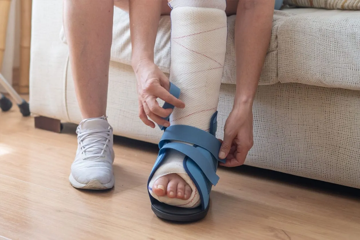 A patient wearing a boot for recovery after an ankle surgery procedure
